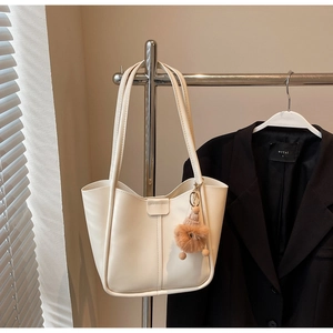 Macro detail of cream white tote bag featuring premium texture and plush ball charm