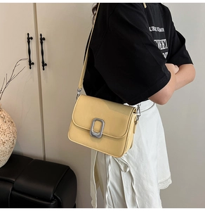 Close-up of a small yellow square crossbody bag with a silver metal buckle and PU leather