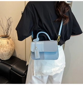 Detail view of light blue contrast handbag with woven texture and gold metal hardware