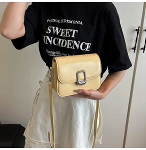 Close-up of pale yellow PU leather crossbody bag with vintage silver metal buckle detail