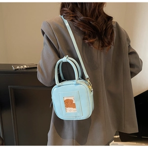 Detail of light blue patent leather handbag featuring a cute cartoon dog card slot