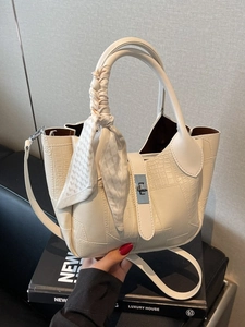 Chic beige bucket bag with crocodile texture and silk scarf handle on hand-held display