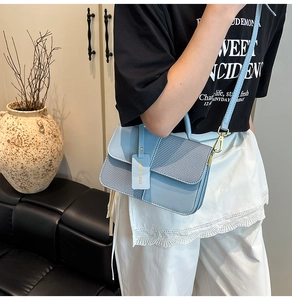 Close-up of light blue crossbody bag featuring contrast texture and gold metal hardware