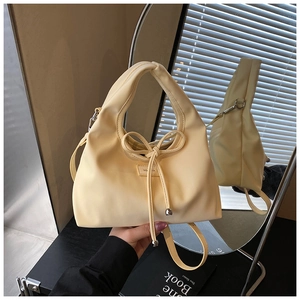 Detail of a creamy yellow handbag with bow tie and silver beads in a mirror reflection