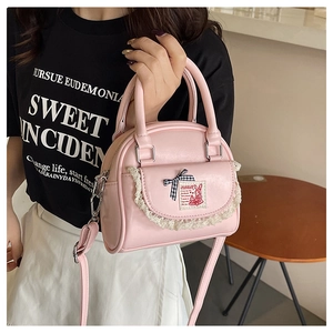 Detailed shot of pink shell bag featuring lace pockets and checkered ribbon bow decoration