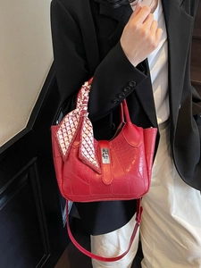 Red crocodile embossed bucket bag with silver twist lock and decorative scarf handle