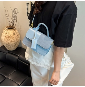 Detail of light blue PU leather handbag with woven texture and gold hardware accessories