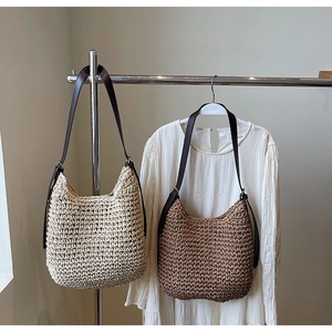 Dettaglio borsa tote in paglia intrecciata a mano con tracolla regolabile in pelle