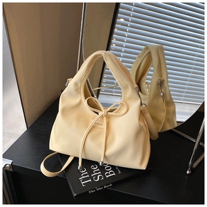Detail of light yellow bucket bag with bow drawstring and NO FILTER logo on black desk