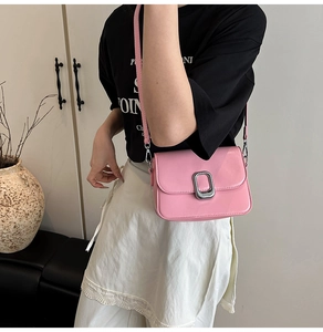 Pink faux leather shoulder bag with silver buckle worn by a model in casual setting