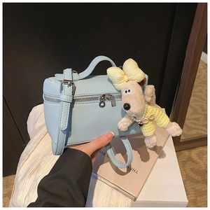 Light blue box bag detail with lychee leather texture and cute dog plush charm