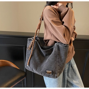 Detail of grey denim tote bag with ethnic woven rope handle shown on female model