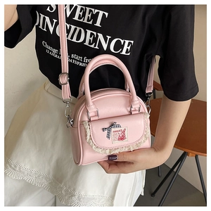Close-up of pink shell-shaped crossbody bag with lace trim, bow, and rabbit embroidery