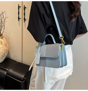Light blue crossbody bag with leather patchwork and gold metal lock shown on a model