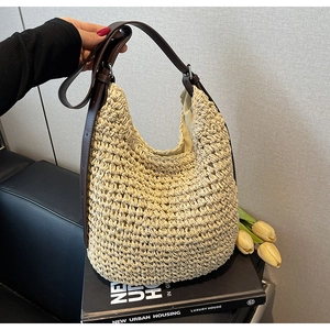 Dettaglio laterale di borsa hobo in paglia intrecciata beige con manico in pelle