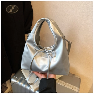 Detail of silver metallic tote bag with bow drawstring and brand nameplate accessory
