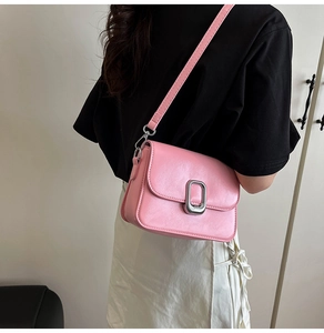 Close-up of pink square PU leather crossbody bag with silver buckle worn by a model