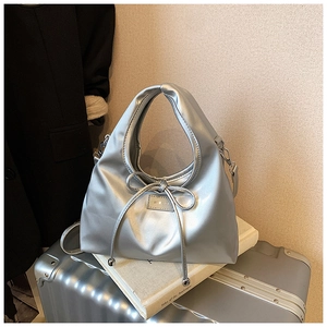 Close-up of silver metallic tote bag with bow detail and adjustable shoulder strap