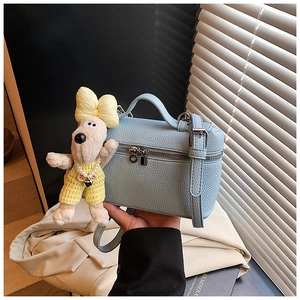 Detailed close-up of light blue box bag with lychee texture and plush dog charm