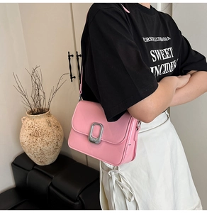 Pink crossbody bag with large silver buckle shown in a lifestyle casual setting