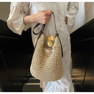 Dettaglio della borsa a secchiello in paglia intrecciata con tracolla marrone scuro