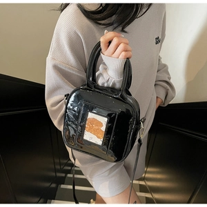 Detail of black glossy patent leather crossbody bag with a clear card slot for women