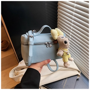 Detail of light blue pebble leather box bag featuring a cute beige dog plush charm