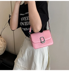 Close-up of a pink square shoulder bag featuring a silver lock and adjustable strap