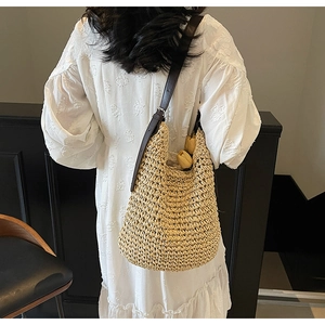 Dettaglio della borsa hobo in paglia intrecciata a mano con tracolla in pelle su pizzo