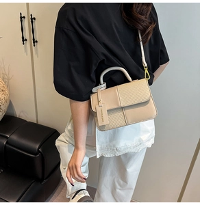 Detail of a beige patchwork crossbody bag featuring textured contrast and gold hardware