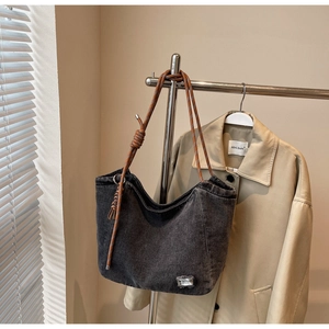 Detail of dark gray washed denim tote with bicolor rope strap and silver logo tag