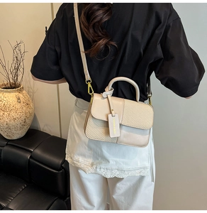 Close-up of contrast beige flap bag with woven texture and a fashion tag detail