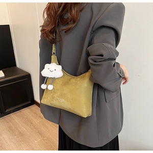 Close-up of mustard yellow suede shoulder bag with a cute white cloud plush pendant