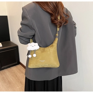 Detail of mustard green faux leather crossbody bag with a white cloud plush charm