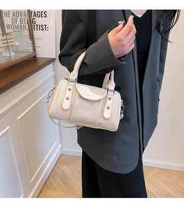 Detail der cremeweißen Stepptasche mit Metallnieten und verstellbarem Schultergurt