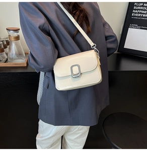 Detail of a creamy white square crossbody bag with a sleek silver metal buckle closure
