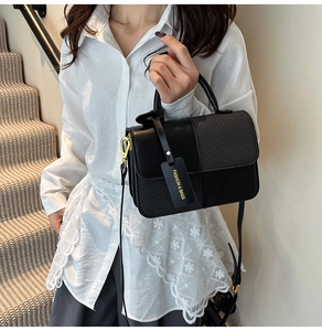 Detail of black crossbody bag featuring smooth leather texture and gold hardware accents