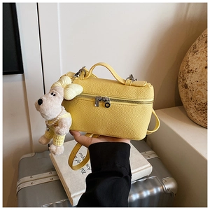 Detail of yellow lychee texture vanity bag with cute dog plush pendant and top handle