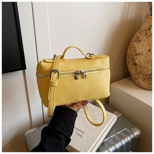 Detail of yellow pebbled leather box bag with silver hardware and top handle