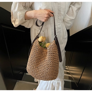 Dettaglio borsa tote in paglia intrecciata con tracolla in PU su scale bianche e nere