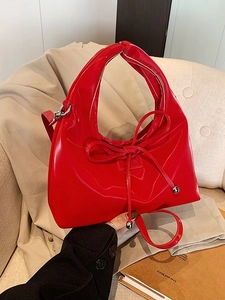 Vibrant red patent leather hobo handbag with bow detail and adjustable shoulder strap
