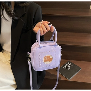 Detail of lavender square handbag with teddy bear window on a wooden staircase