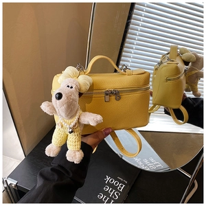 Detail of yellow lychee texture box bag with a cute white puppy plush charm and top handle