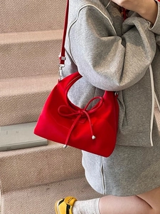 Stylish red bucket bag with bow detail and silver beads on a fashion model