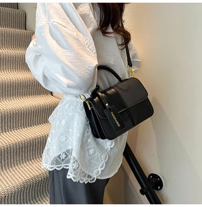 Close-up of black crossbody bag with woven texture, golden buckle and fashion tag detail