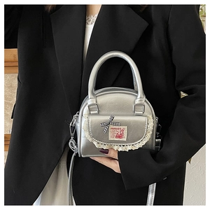 Silver shell-shaped handbag detail featuring a lace flap and red checkered bow