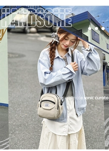 Detail of a beige functional crossbody bag with drawstring pocket and adjustable strap
