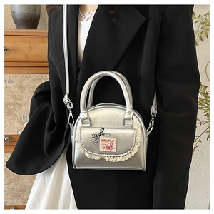 Detail of silver metallic Boston bag with lace trim, bow and cute bunny patch