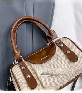 Detail von Fischgräten-Webstoff und braunem Ledergriff an einer stilvollen Boston-Handtasche