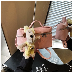 Pink lychee grain box bag detail with silver double zippers and plush puppy charm